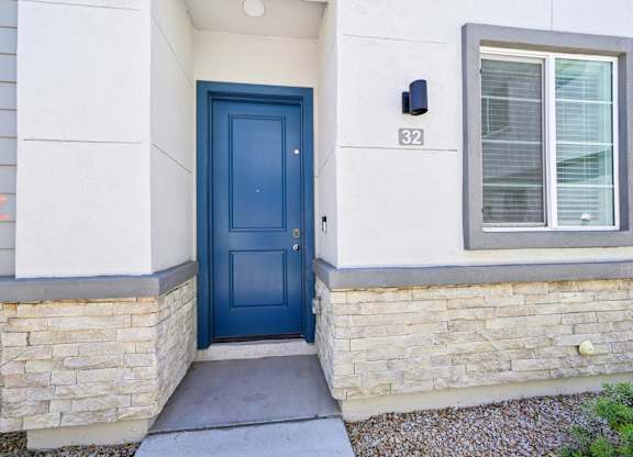 Baseline on 16th townhome entrance with a blue door is on the left side of a house with a stone wall.