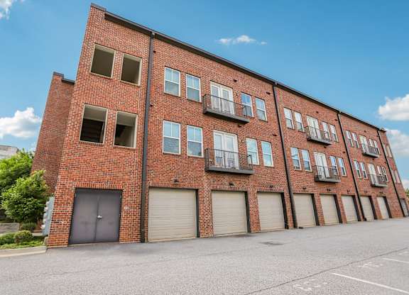 A red brick building with a parking lot in front.