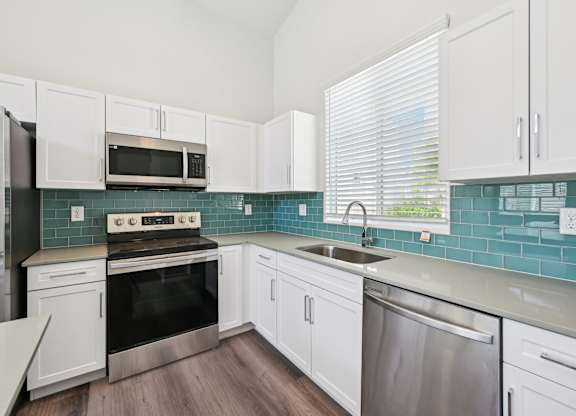 Baseline on 16th townhome kitchen with white cabinets and a stainless steel dishwasher.