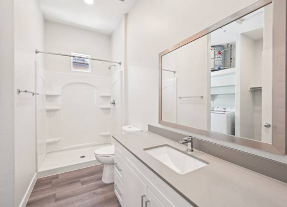 A white bathroom with a toilet, sink, and mirror.