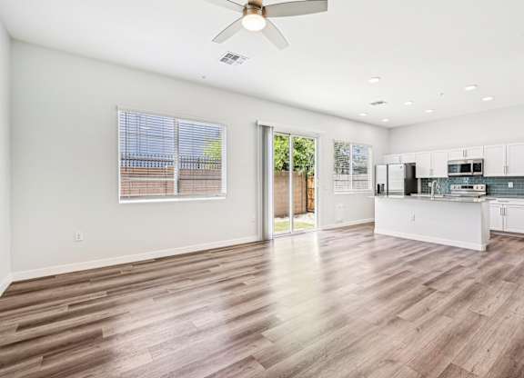 Baseline on 16th townhome spacious kitchen and living room with wood flooring and white walls.