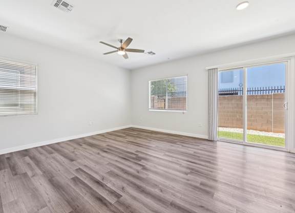 Baseline on 16th townhome room with a ceiling fan and sliding glass doors.