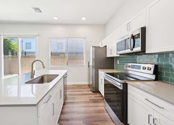 Baseline on 16th townhome kitchen with white cabinets and a wooden floor.