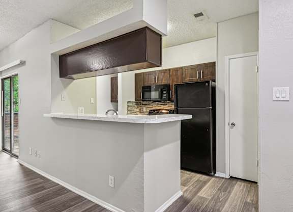 A kitchen with a black refrigerator and a white counter.