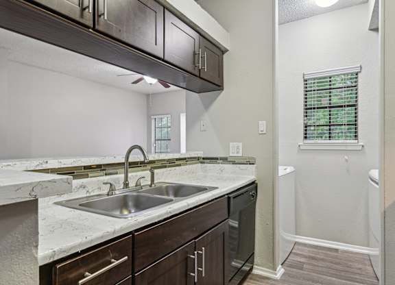 A kitchen with a marble countertop and dark wood cabinets.