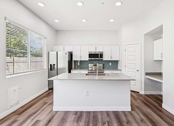 Baseline on 16th townhome kitchen with white cabinets and a wooden floor.