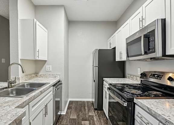 A kitchen with a black refrigerator, stove, and oven.