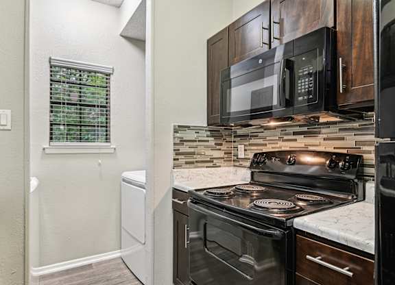 A kitchen with a black stove top oven and a black microwave above it.