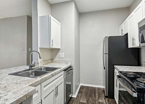A kitchen with a black refrigerator and white cabinets.