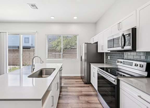 Baseline on 16th townhome modern kitchen with white cabinets and stainless steel appliances.