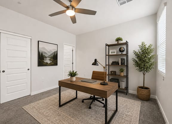 A room with a desk, chair, and a plant.