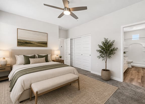 A bedroom with a bed, a bench, a ceiling fan, and a painting on the wall.