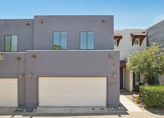A modern house with a grey facade and white garage doors.