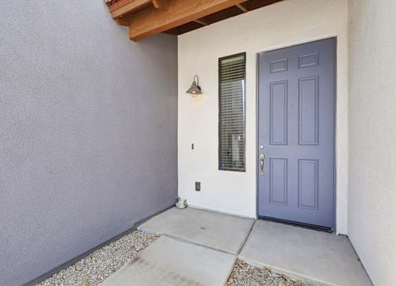 A blue door is on the right side of a white wall.