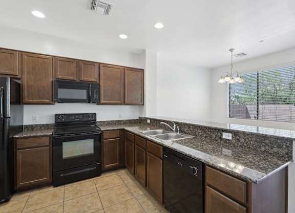 A kitchen with dark wood cabinets and black appliances.