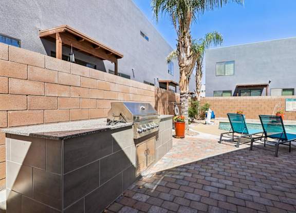 A modern outdoor kitchen area with a grill and seating area.