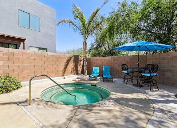 A small pool in a backyard with a table and chairs.