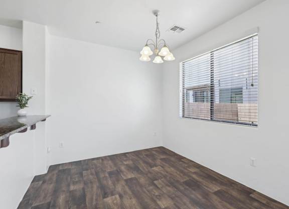 A room with wooden flooring and a window with blinds.