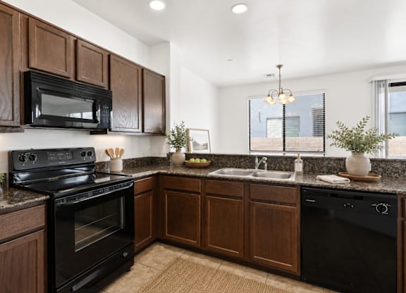 A kitchen with dark wood cabinets and black appliances.