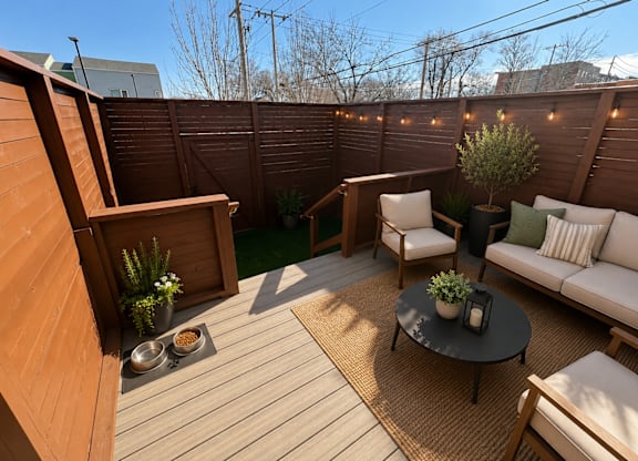 A wooden deck with a white couch and a table with a plant on it.