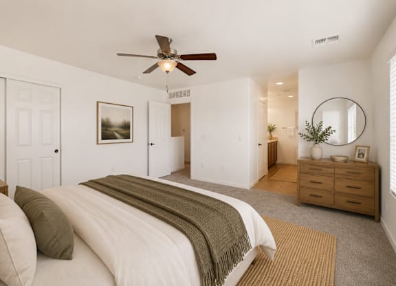 A bedroom with a large bed and a ceiling fan.