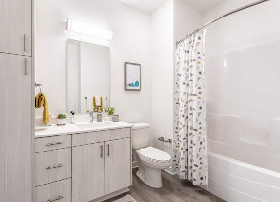 A white bathroom with a toilet, sink, and shower.