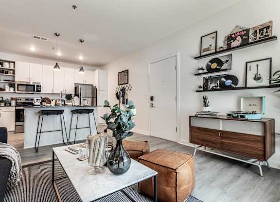A modern living room with a kitchen in the background.