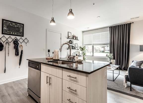 A modern kitchen with a black countertop and stainless steel appliances.