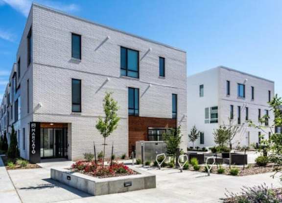 A modern building with a grey facade and a small garden in front.