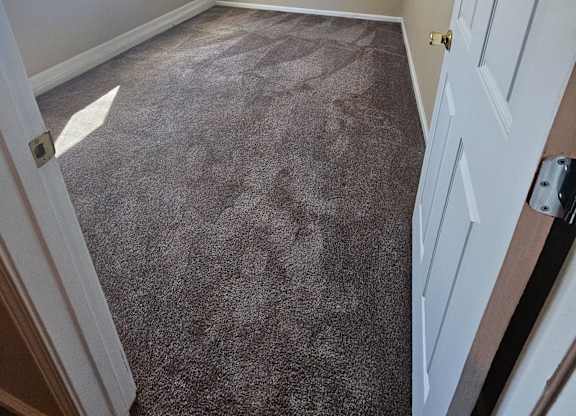 an empty bedroom with a carpeted floor and a window