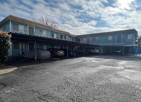 an empty parking lot in front of a motel with a cloudy sky