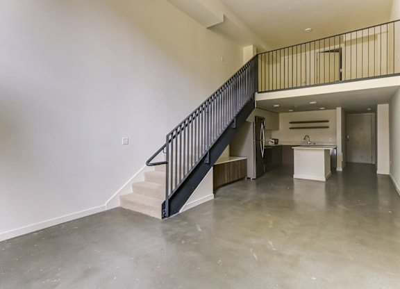A black metal railing on a staircase in a large empty room.