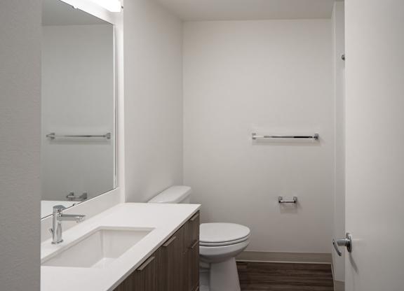 A white bathroom with a toilet, sink and mirror.