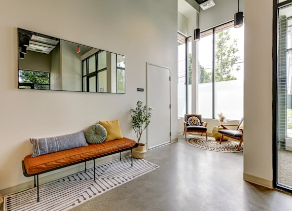 A room with a bench, a mirror, and a plant.