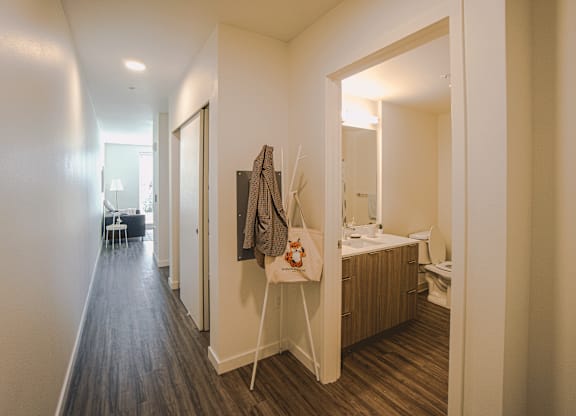 A small bedroom with a bed, a mirror, a toilet, and a wooden floor.