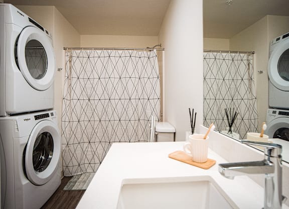 A white washing machine is stacked on top of another in a laundry room.