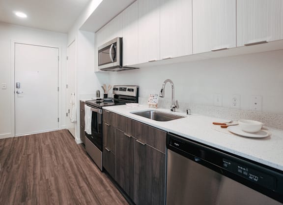 A kitchen with dark wood floors and white cabinets.