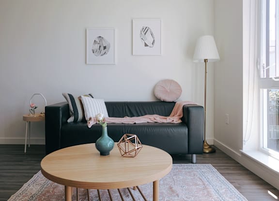 A living room with a black couch, a wooden table, and two framed pictures on the wall.