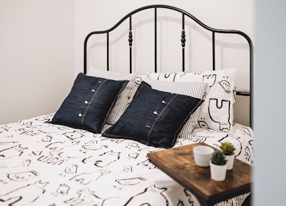 A bed with a white comforter and two blue denim pillows.