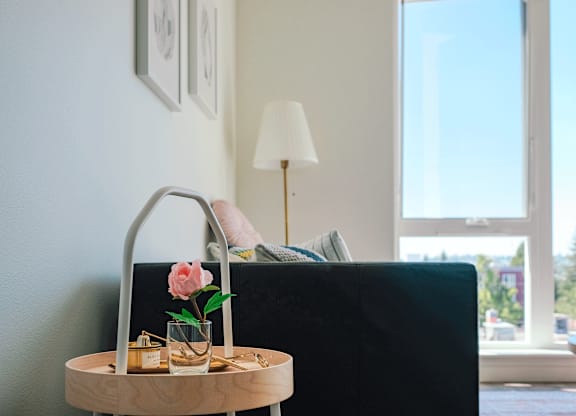 A table with a pink flower and a vase on it.
