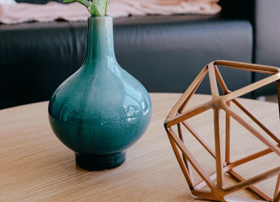 A blue vase with a white flower sits on a table next to a geometric structure.