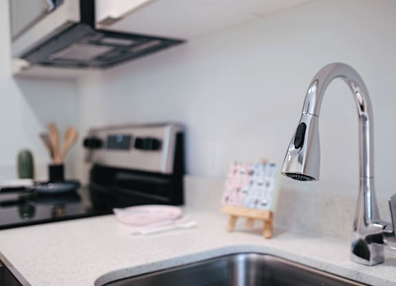A kitchen sink with a chrome faucet and a small wooden stand with cards on it.