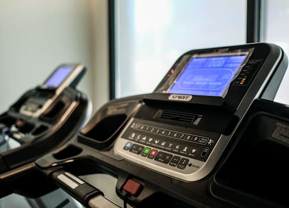 Two treadmills with digital displays and control panels are shown.