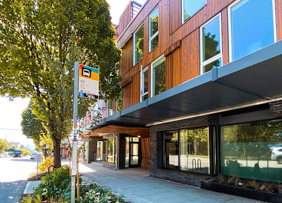 A modern building with a wooden facade and a green tree beside it.