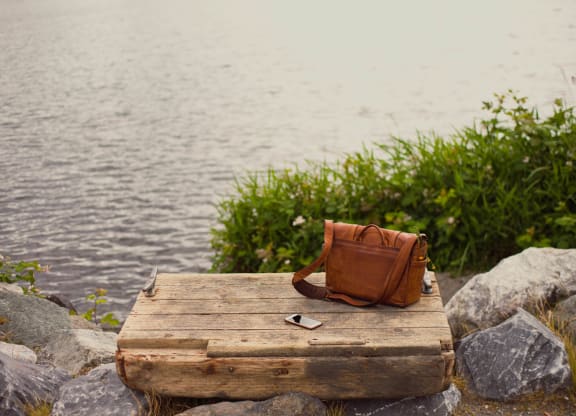 a purse and cell phone sitting on a dock on the water