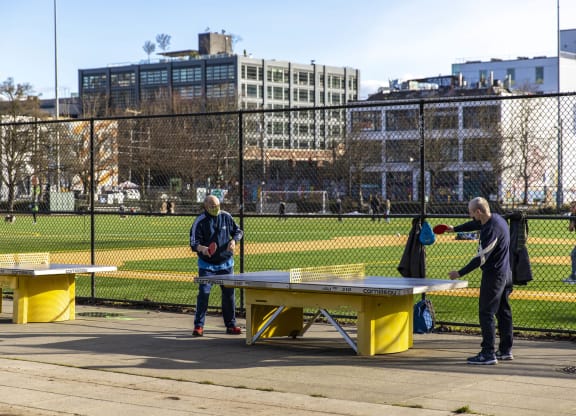 people playing ping pong on benches in a park