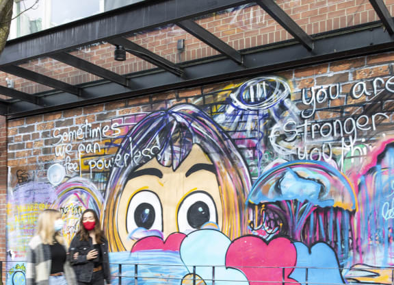 people walking past a building with graffiti on it