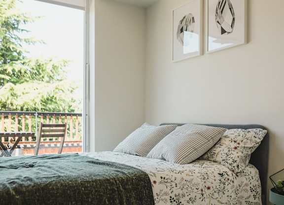 A bedroom with a bed, pillows, and two framed pictures on the wall.