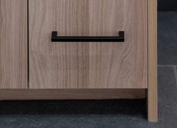 A wooden drawer with a black handle is placed on a grey floor.