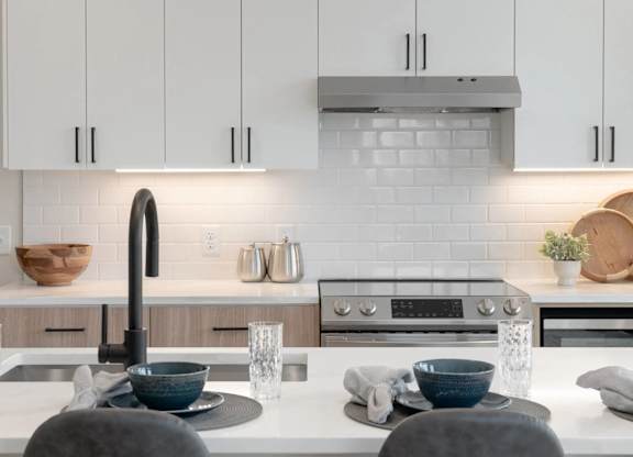A modern kitchen with a white countertop and a black faucet.